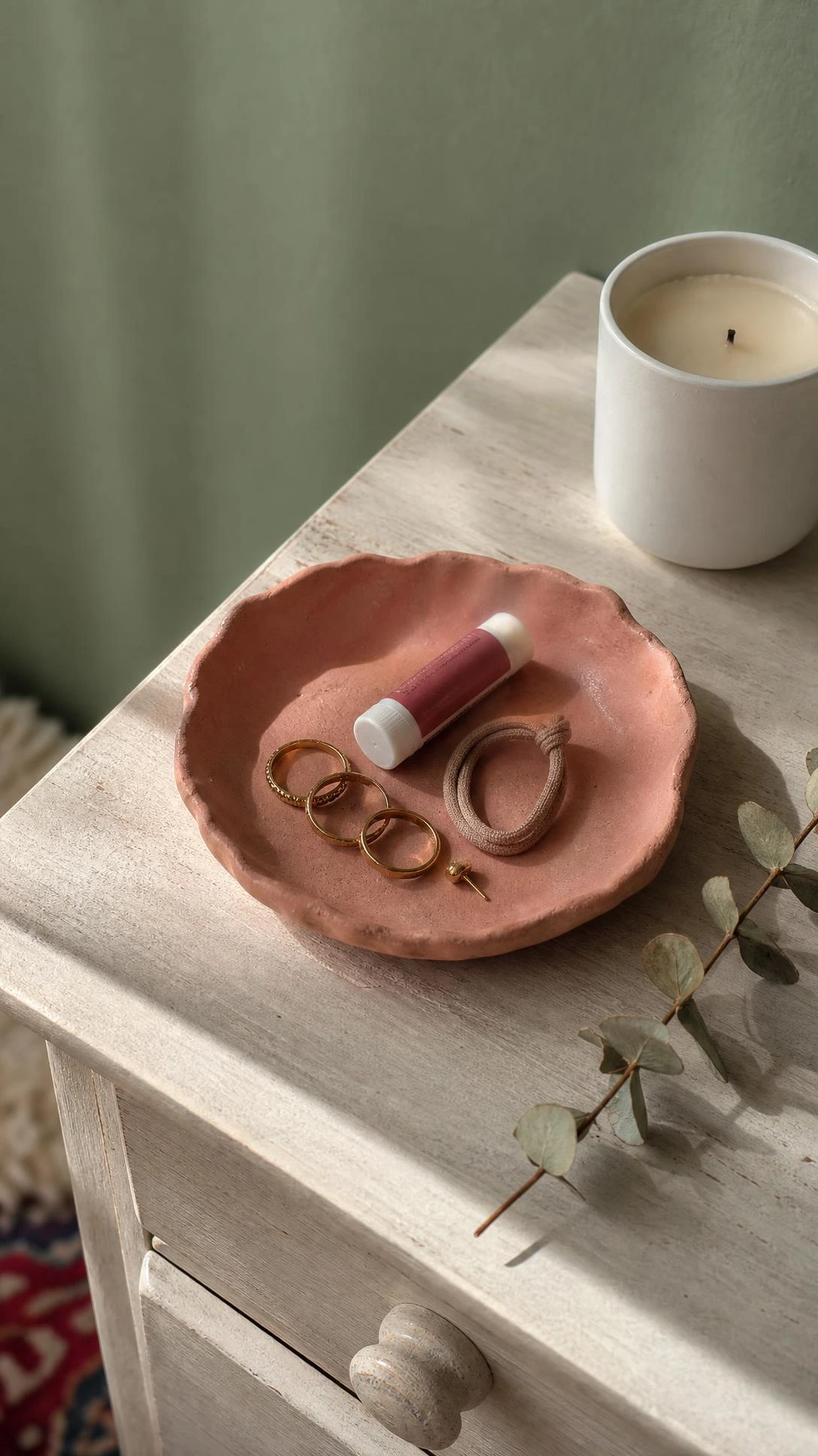 Handmade air-dry clay catch-all tray in terracotta-blush with pinched edges resting on a light wood side table — an easy budget home decor DIY