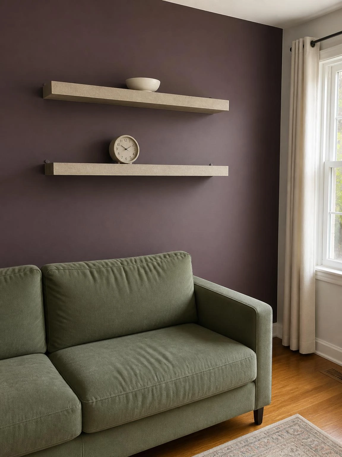 Two stone-colored MDF floating shelves mounted on a muted plum accent wall, holding a ceramic bowl and analog clock in a lived-in living room