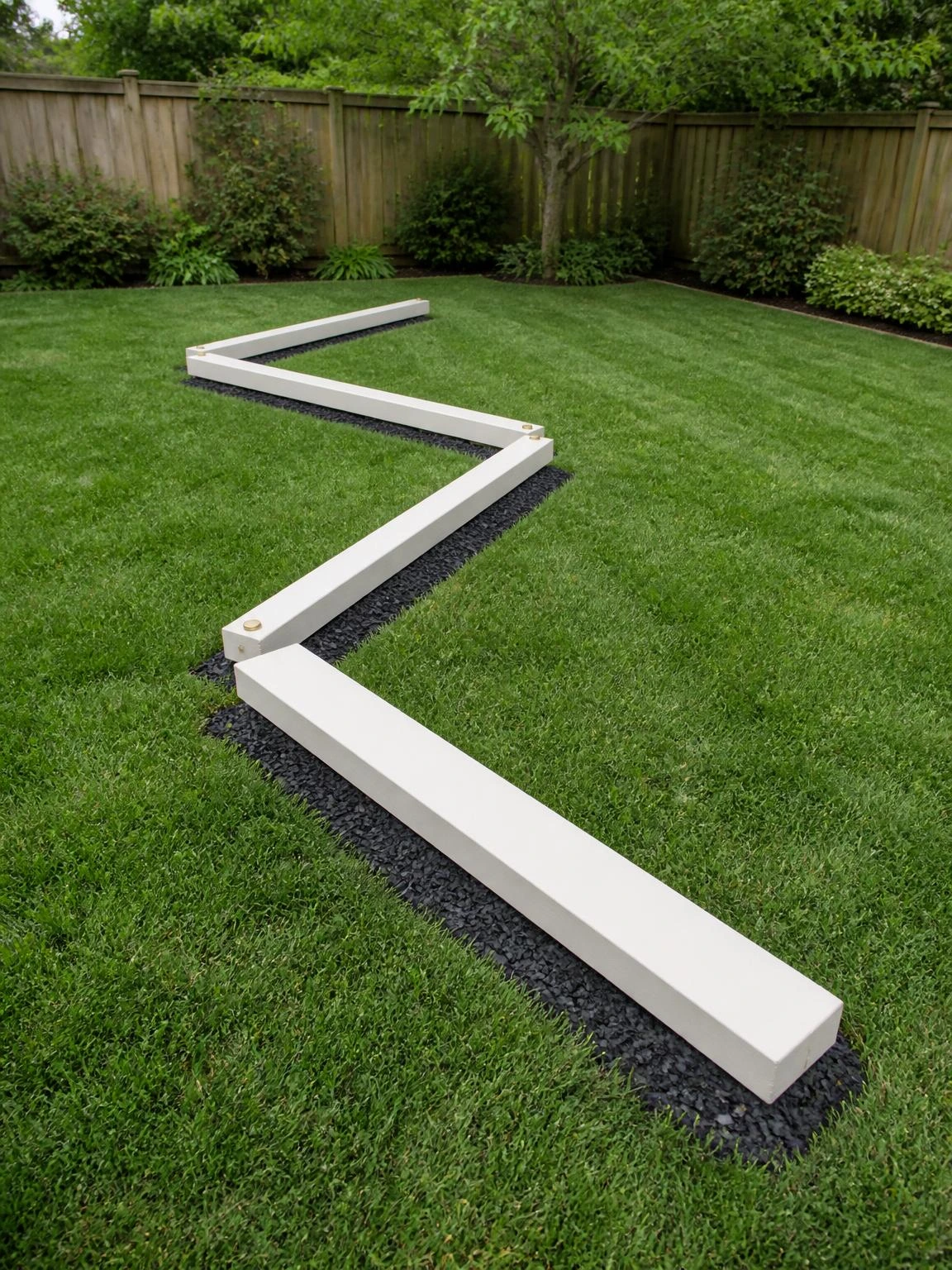 Three cream-painted timber balance beams arranged in a zigzag pattern across a lush backyard lawn, showing a low-to-ground balance beam course kids can actually use
