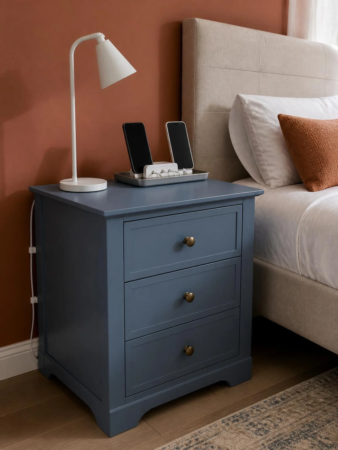 Multi-port USB charging hub on a brushed-steel tray organizes both partners' phones on a soft blue nightstand for clutter-free couple room decor
