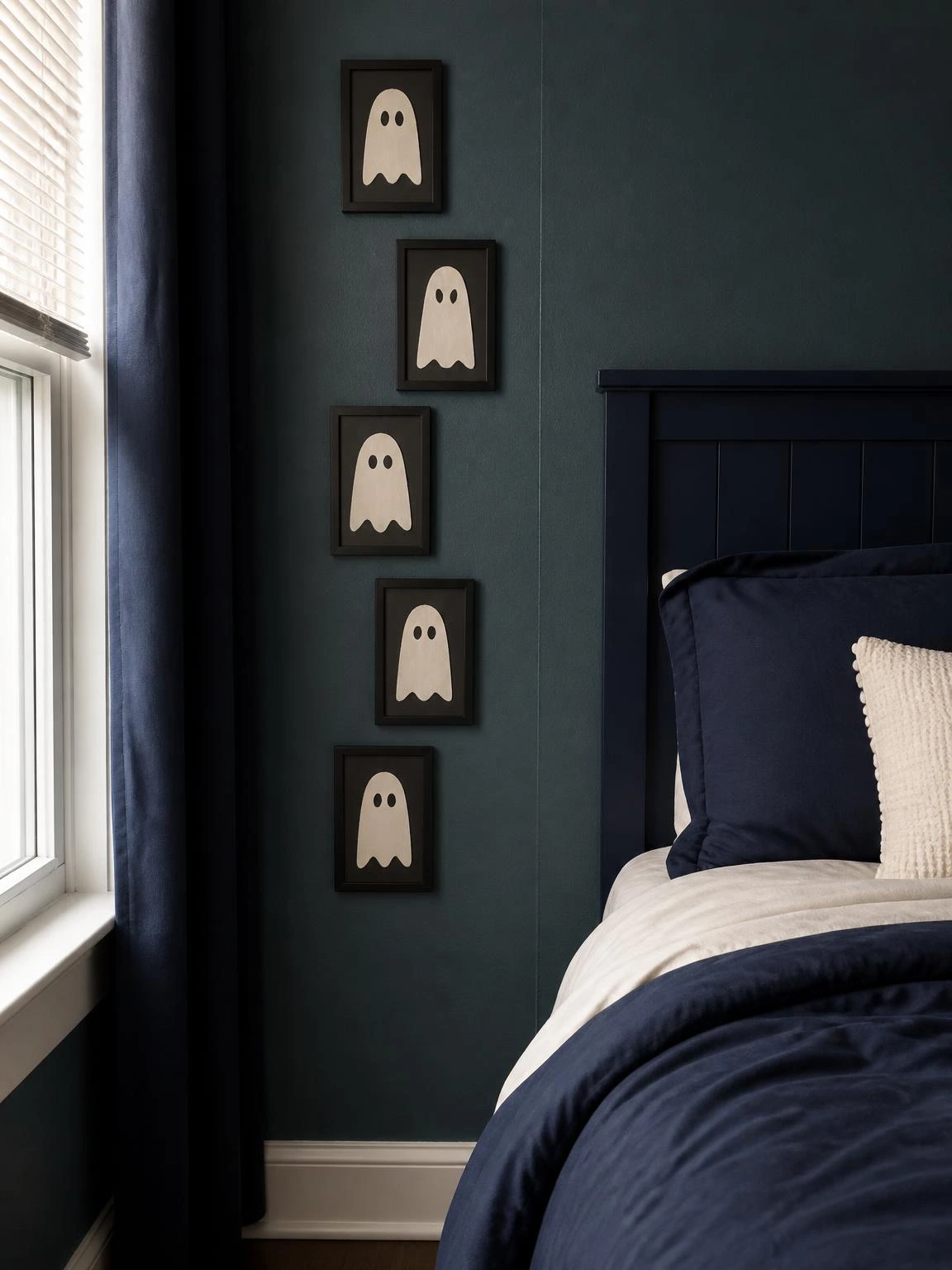 Five handmade ivory paper ghosts form a compact black-framed gallery beside a navy bed, showcasing diy halloween bedroom decor cheap