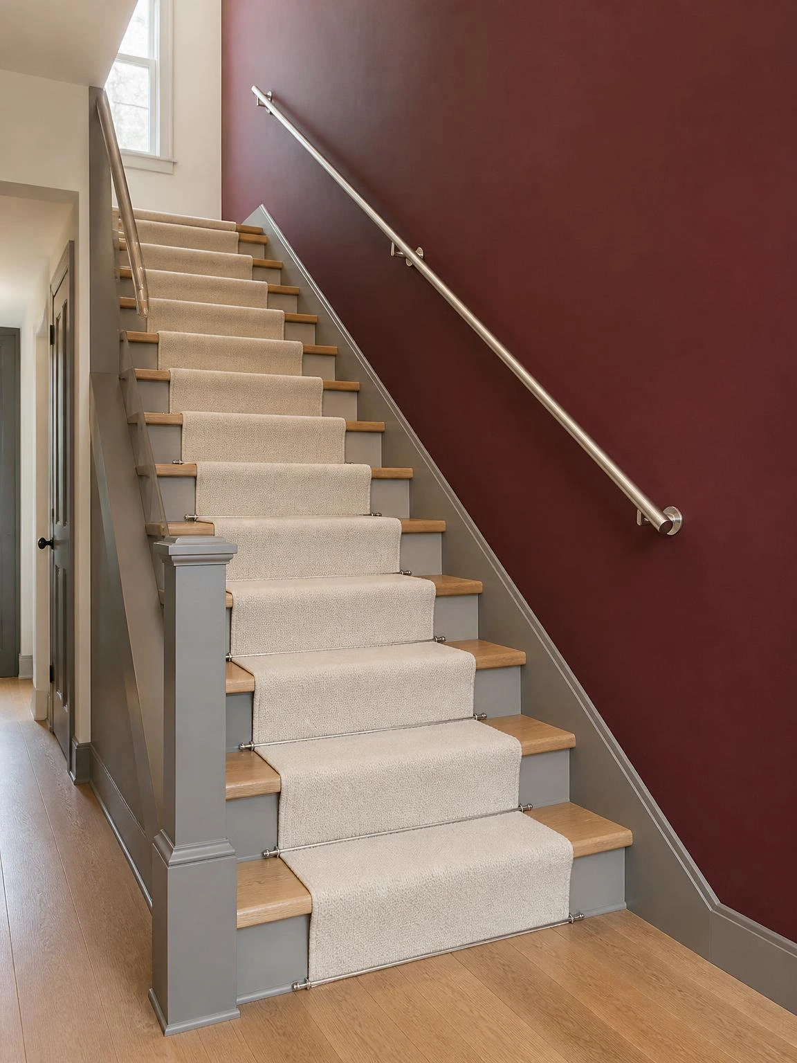 Residential staircase with uninterrupted matte burgundy wall, light oak treads, warm gray risers, and ivory wool runner under soft overcast light