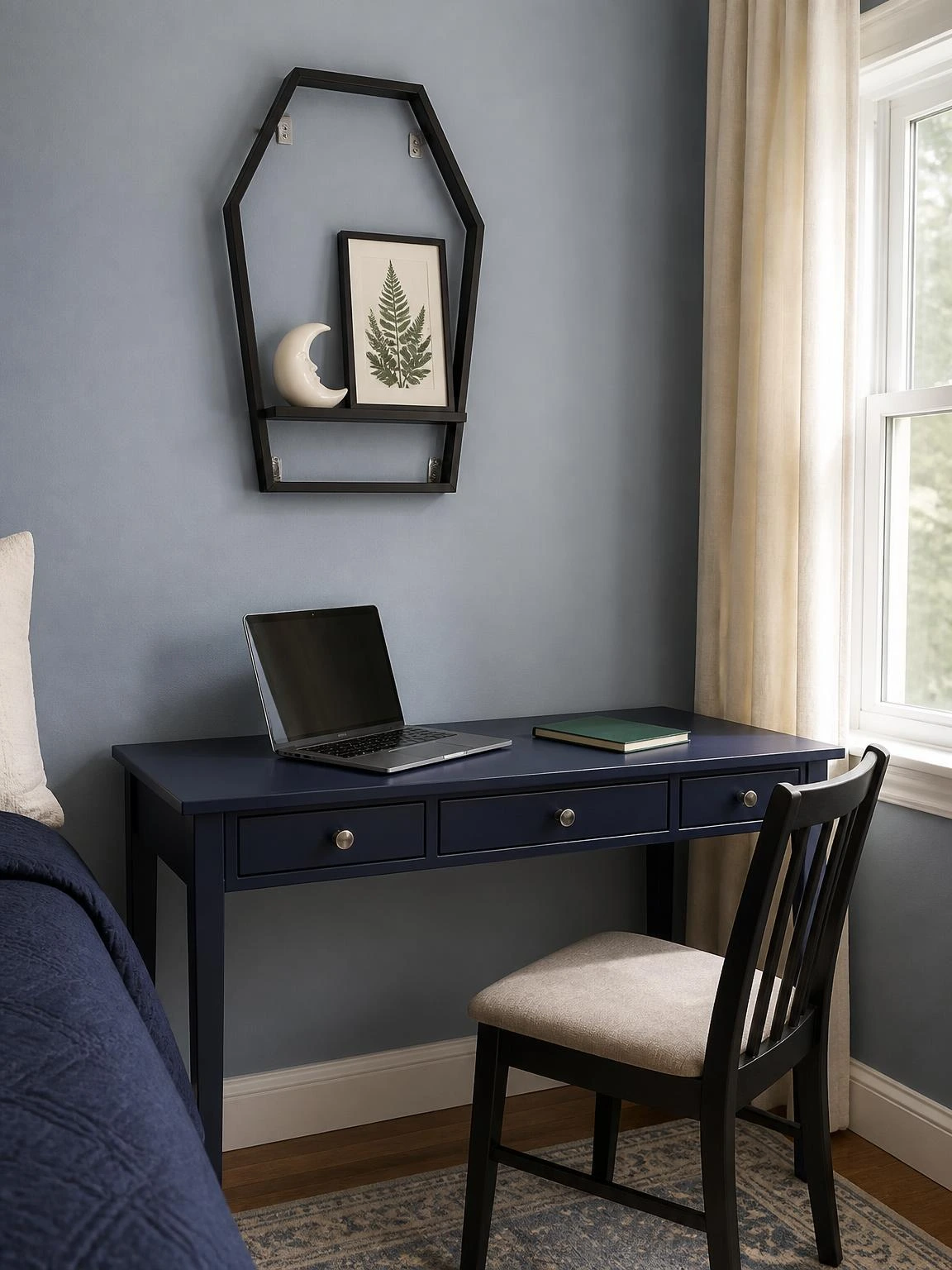Coffin-shaped black metal shelf with an ivory moon and green botanical print above a tidy navy desk, a practical halloween aesthetic bedroom decor idea