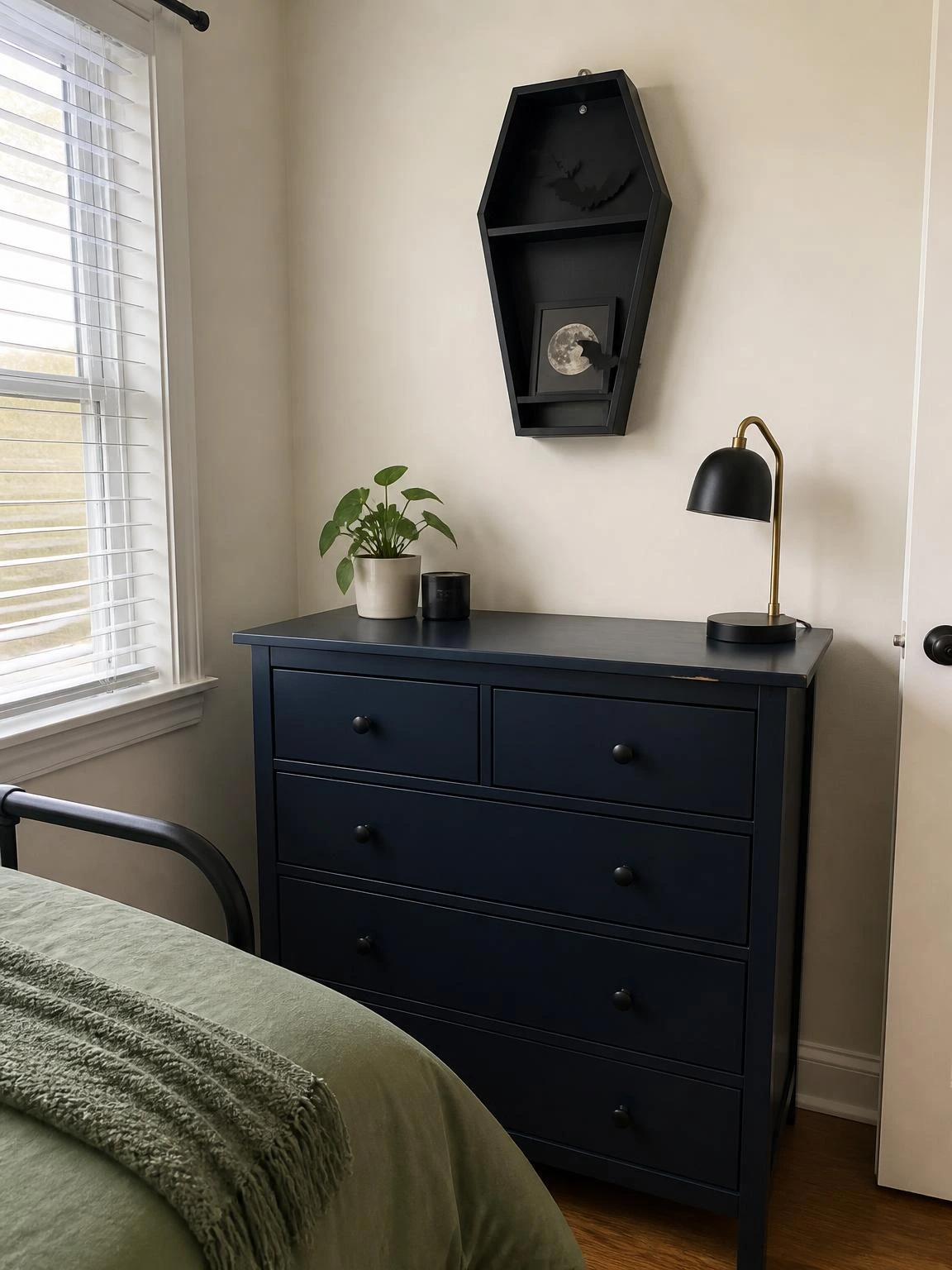 Coffin-shaped black shelf with paper bats above a navy dresser, a cheap DIY Halloween bedroom decor idea