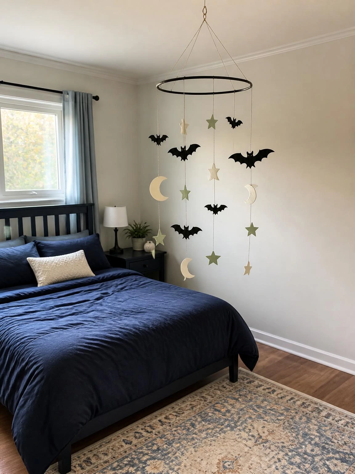 DIY Halloween ceiling mobile with black bats, ivory moons, and green stars floating above a navy bed