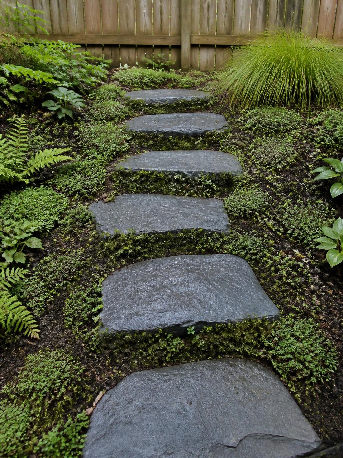 Five Pennsylvania bluestone flagstone steps embedded into a planted garden slope, with creeping thyme filling the gaps — a naturalistic landscape stairs solution