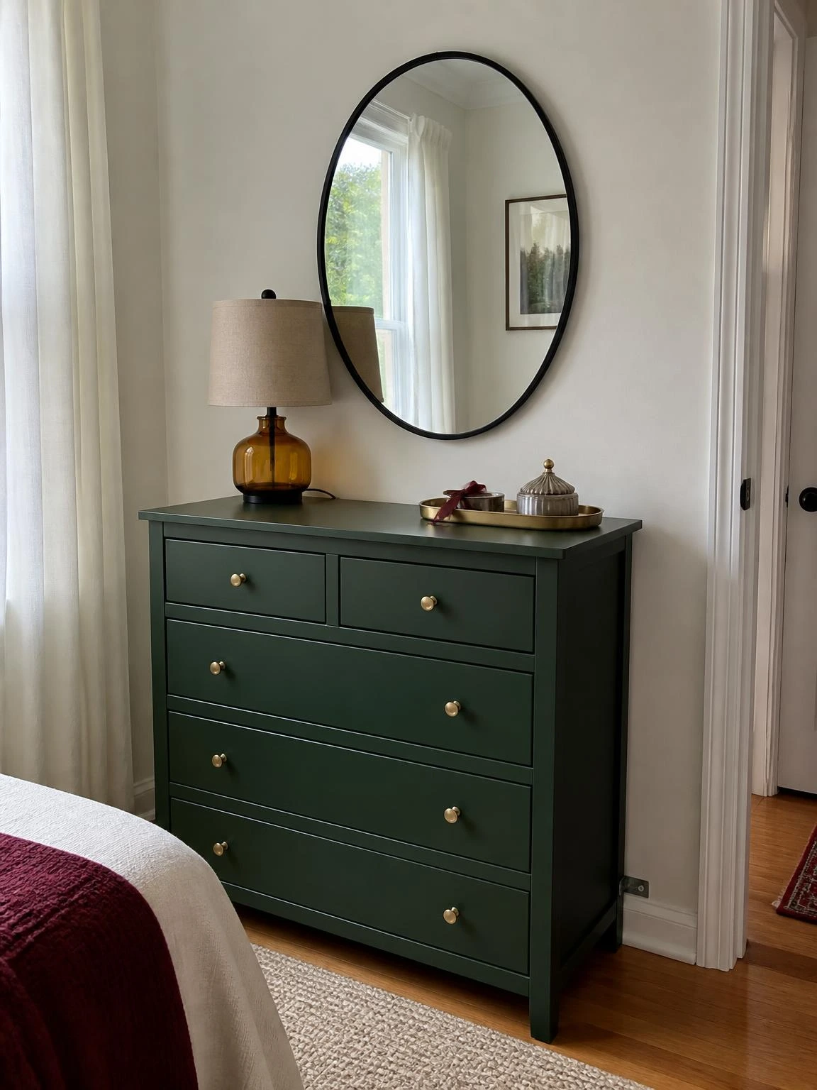 Forest-green dresser styled for halloween aesthetic bedroom decor with an amber lamp, brass tray, and black oval mirror