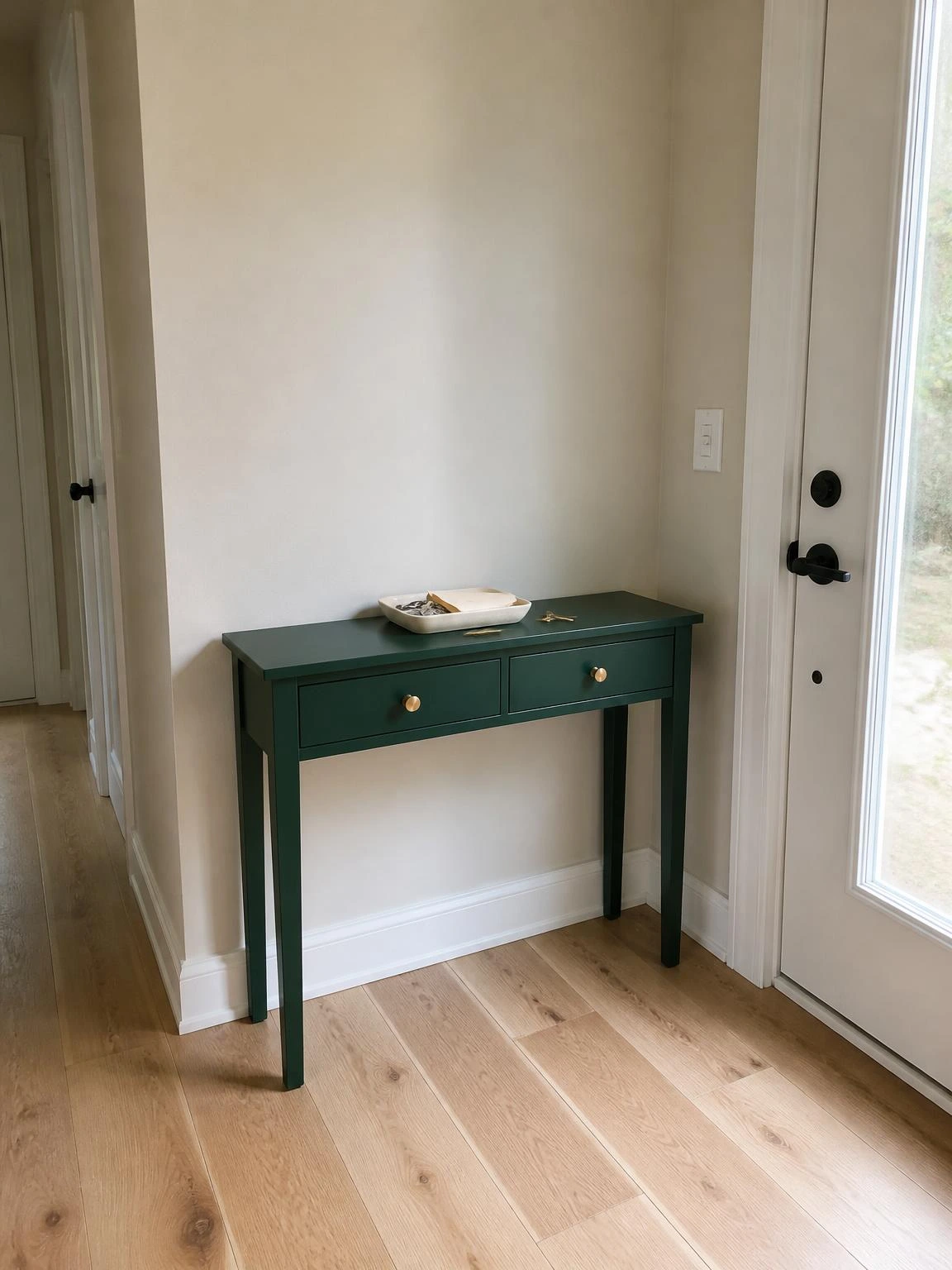 Forest green matte console table with brass drawer pulls styled in a narrow entryway, showing how a bold painted accent piece anchors summer home decor
