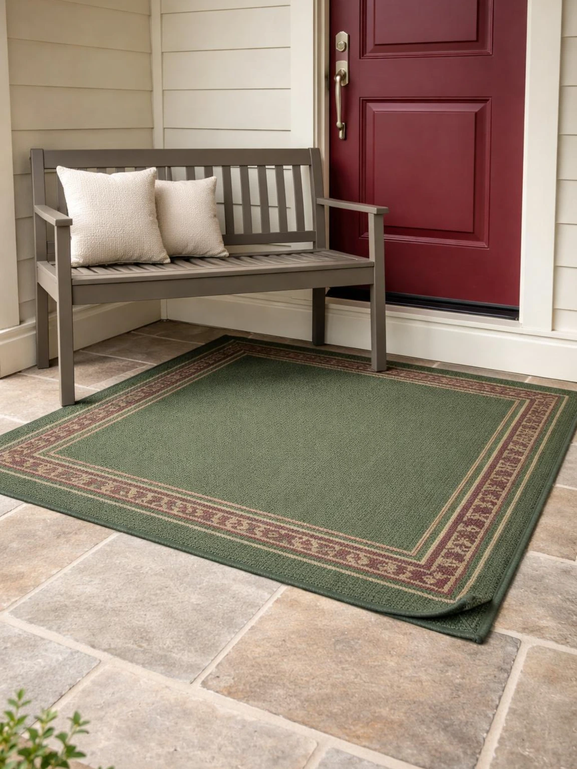 Forest-green fall porch rug with burgundy accents anchors a gray bench beside a burgundy door on a compact contemporary entryway.