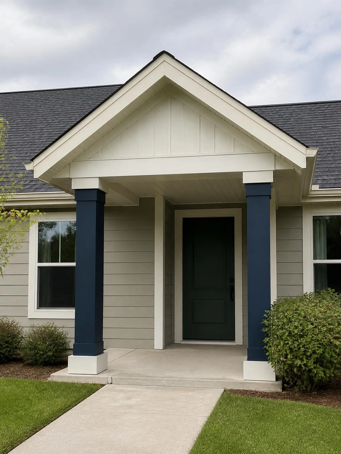 Gable porch roof design with navy painted wood columns and charcoal asphalt shingles on a traditional one-story suburban home