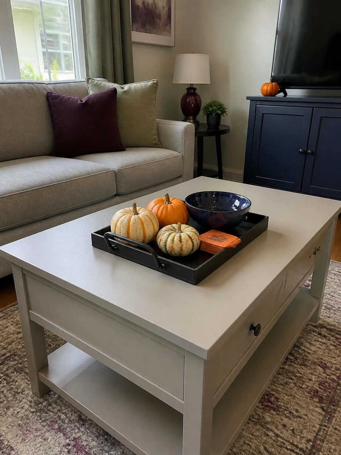 Halloween coffee table decor arranged in a black tray with miniature pumpkins, navy bowl, and orange coasters