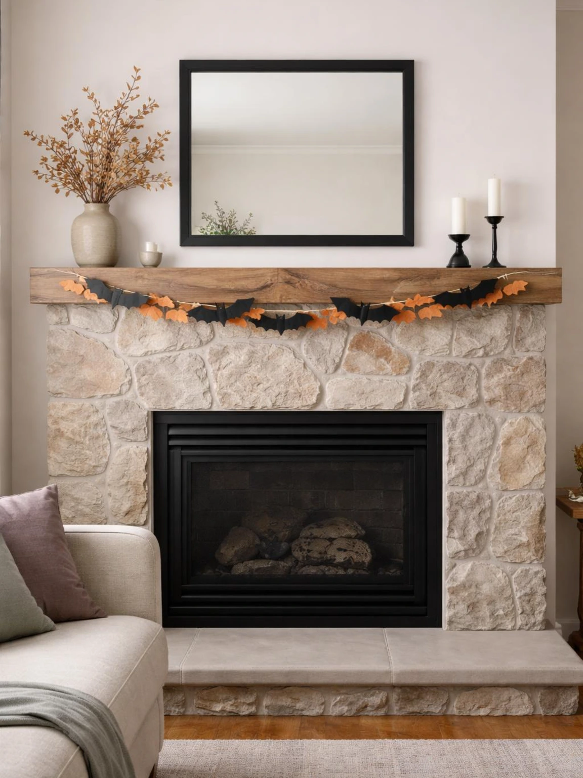 Halloween mantel garland of black paper bats and muted orange felt leaves above a closed fireplace and clear hearth