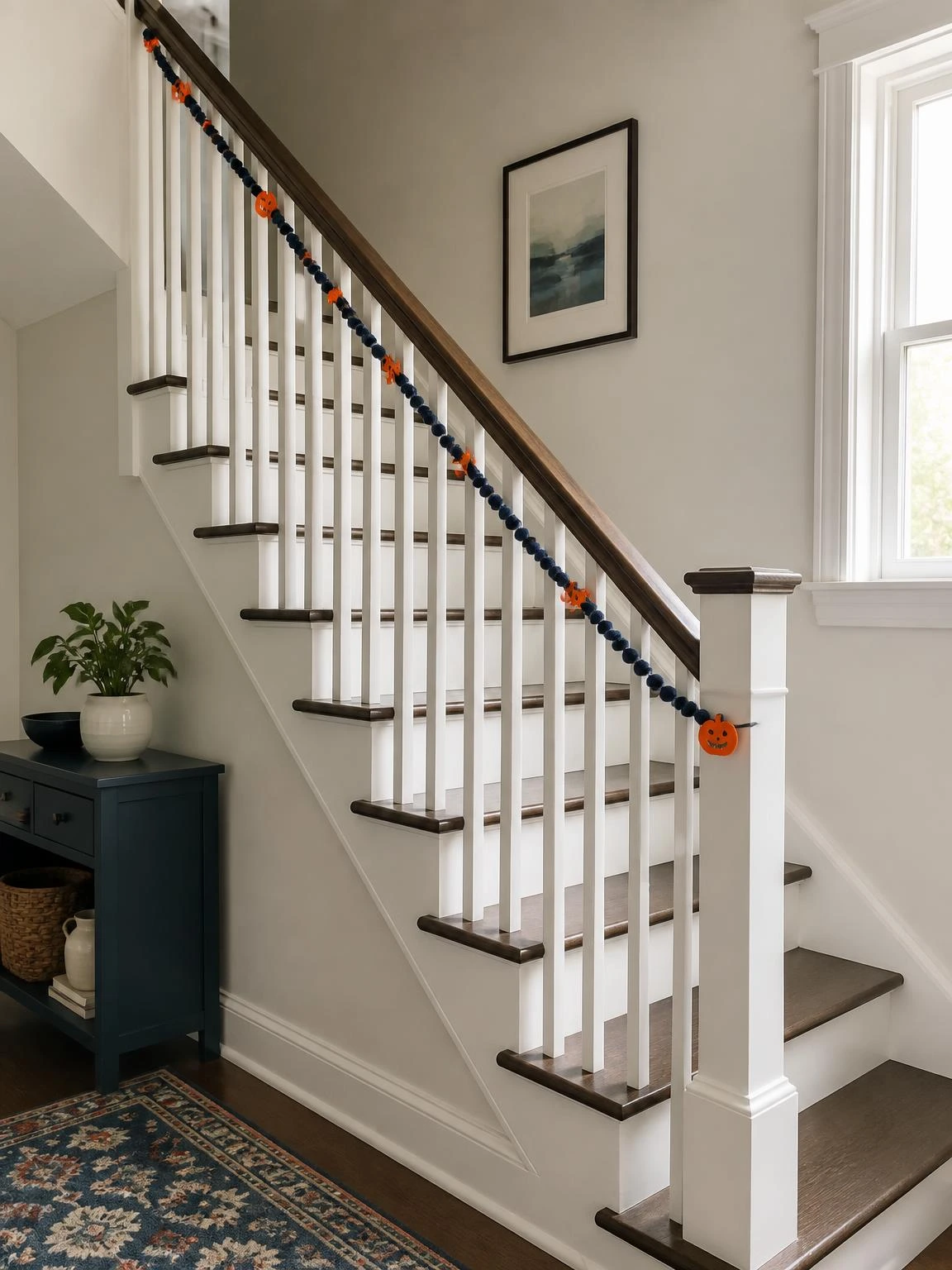 Halloween stair railing decor uses a dark blue garland and orange felt shapes while keeping the handrail clear and safe.