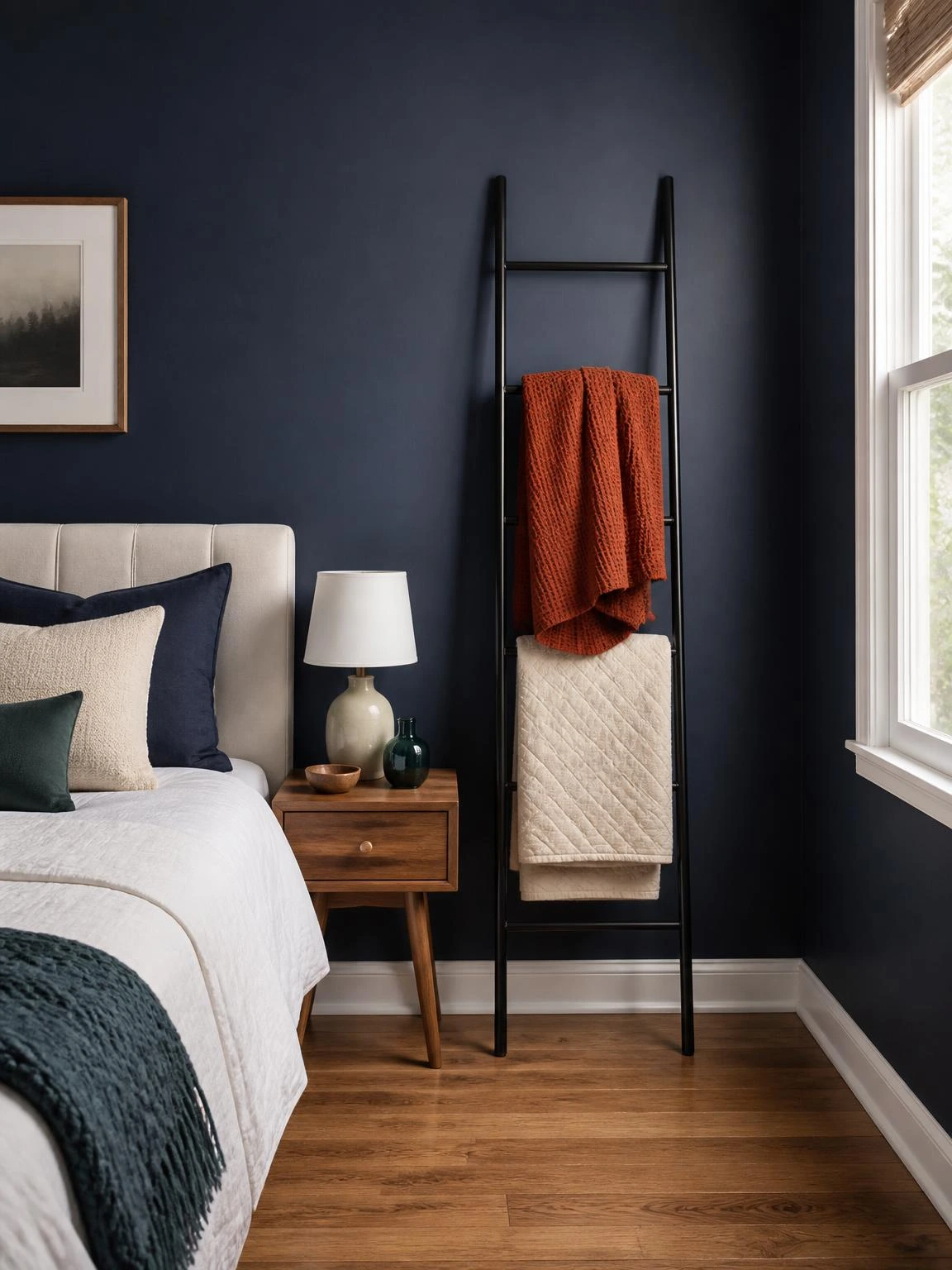 Halloween blanket ladder with rust throw and ivory quilted coverlet against a navy bedroom wall, adding attainable seasonal style