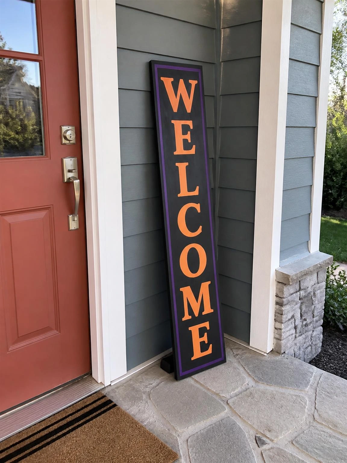 Charcoal Halloween welcome sign with orange lettering and purple border beside a clear residential entryway, a practical Halloween crafts DIY project