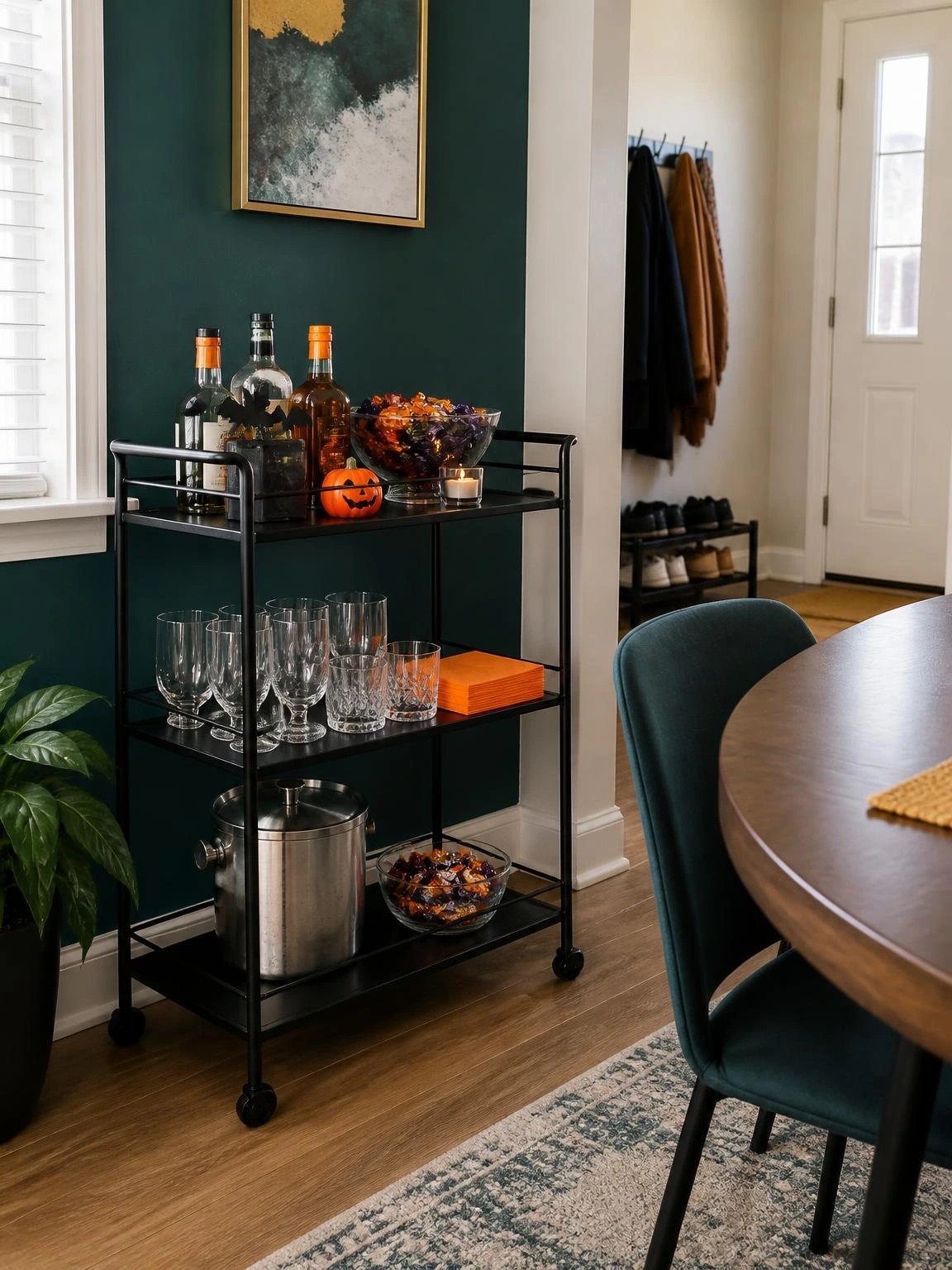 Halloween bar cart with glasses, orange napkins, ice bucket, and wrapped sweets arranged safely in a dining corner
