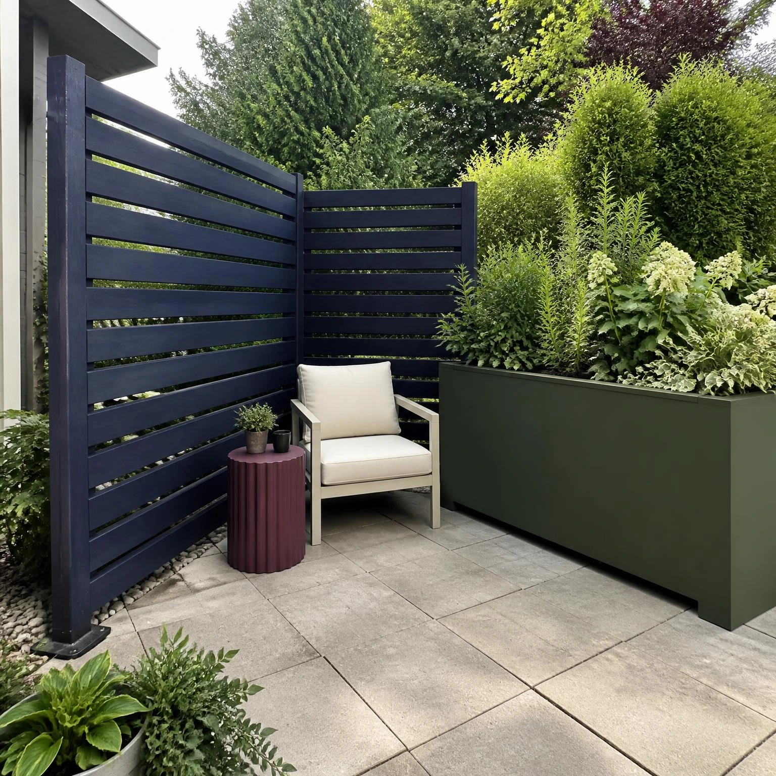 Layered backyard privacy corner with a navy slatted screen and tall green planter forming a private reading zone without a fence
