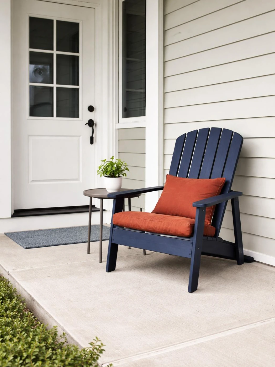 Navy porch chair with a rust cushion and warm-gray table adds colorful fall porch decor beside a clear, accessible entryway.