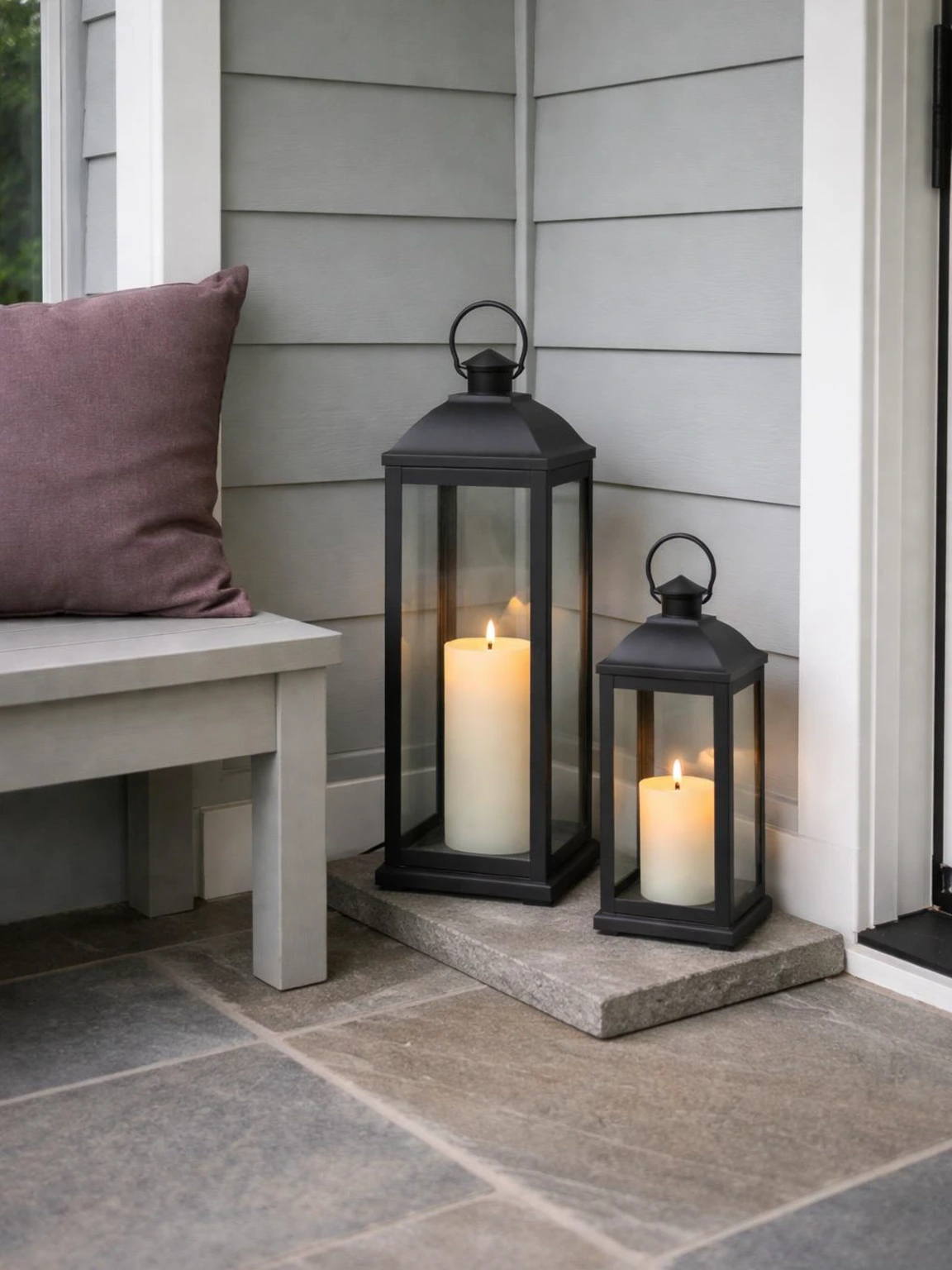 Two charcoal lanterns with ivory LED candles create a safe halloween decorations outdoor corner beside a plum cushion.