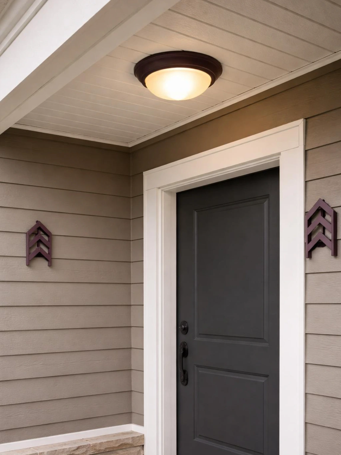 Plum porch ceiling light surround framing a softly glowing entry beside warm-gray siding in colorful fall porch decor