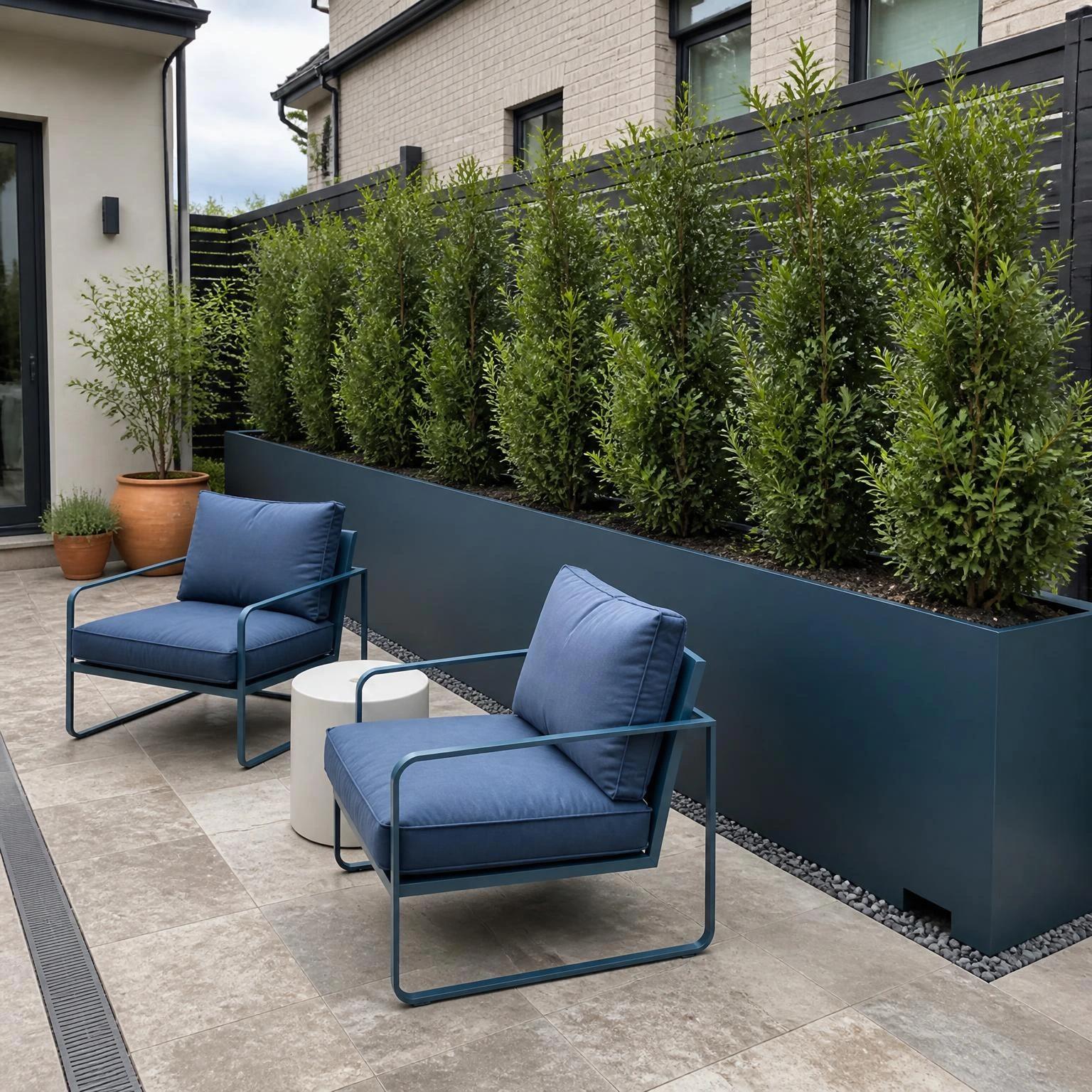 Raised planter privacy hedge screens neighboring windows behind a compact patio seating area, showing a practical fence-free solution.