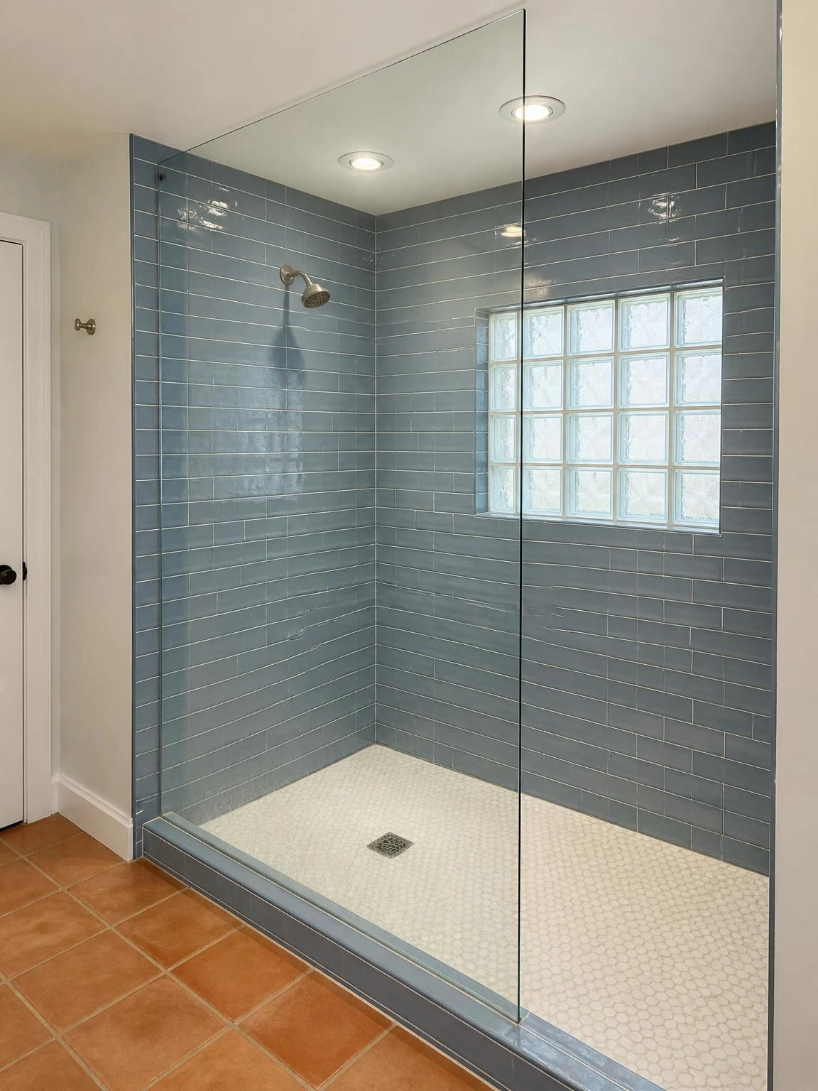 Walk-in shower with dusty-blue subway tile and two recessed ceiling downlights with chrome trim rings mounted flush in the wet zone