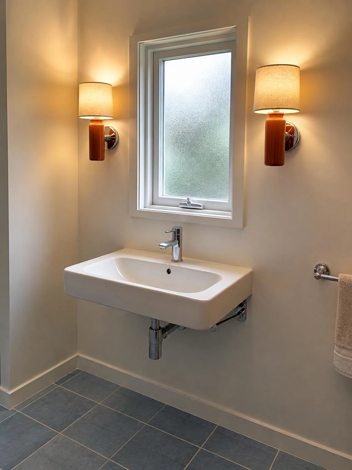 Two terracotta ceramic sconces with linen drum shades flanking a frosted casement window, demonstrating balanced bathroom lighting without a vanity mirror