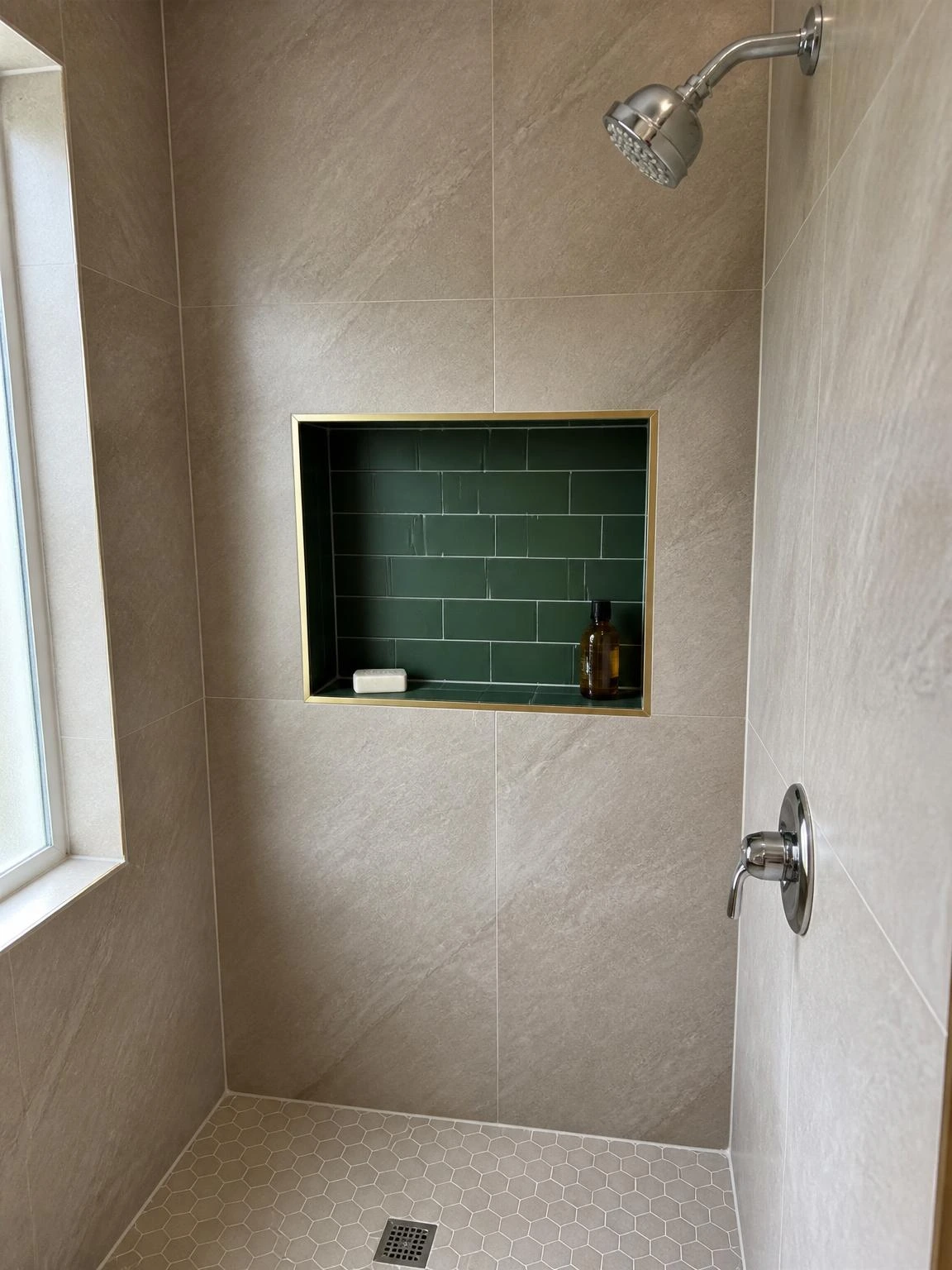 Recessed shower niche lined with forest green subway tile contrasting warm greige wall tile, brass trim detail for a budget bathroom upgrade