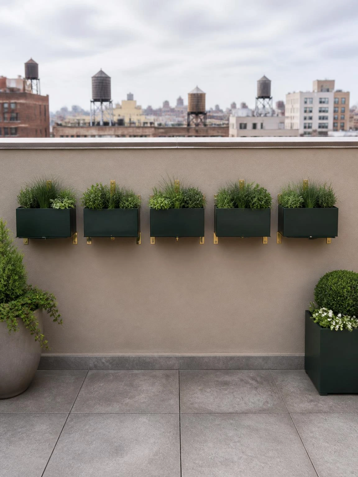 Five powder-coated steel wall planters mounted on a greige parapet wall add vertical greenery to a small rooftop terrace design